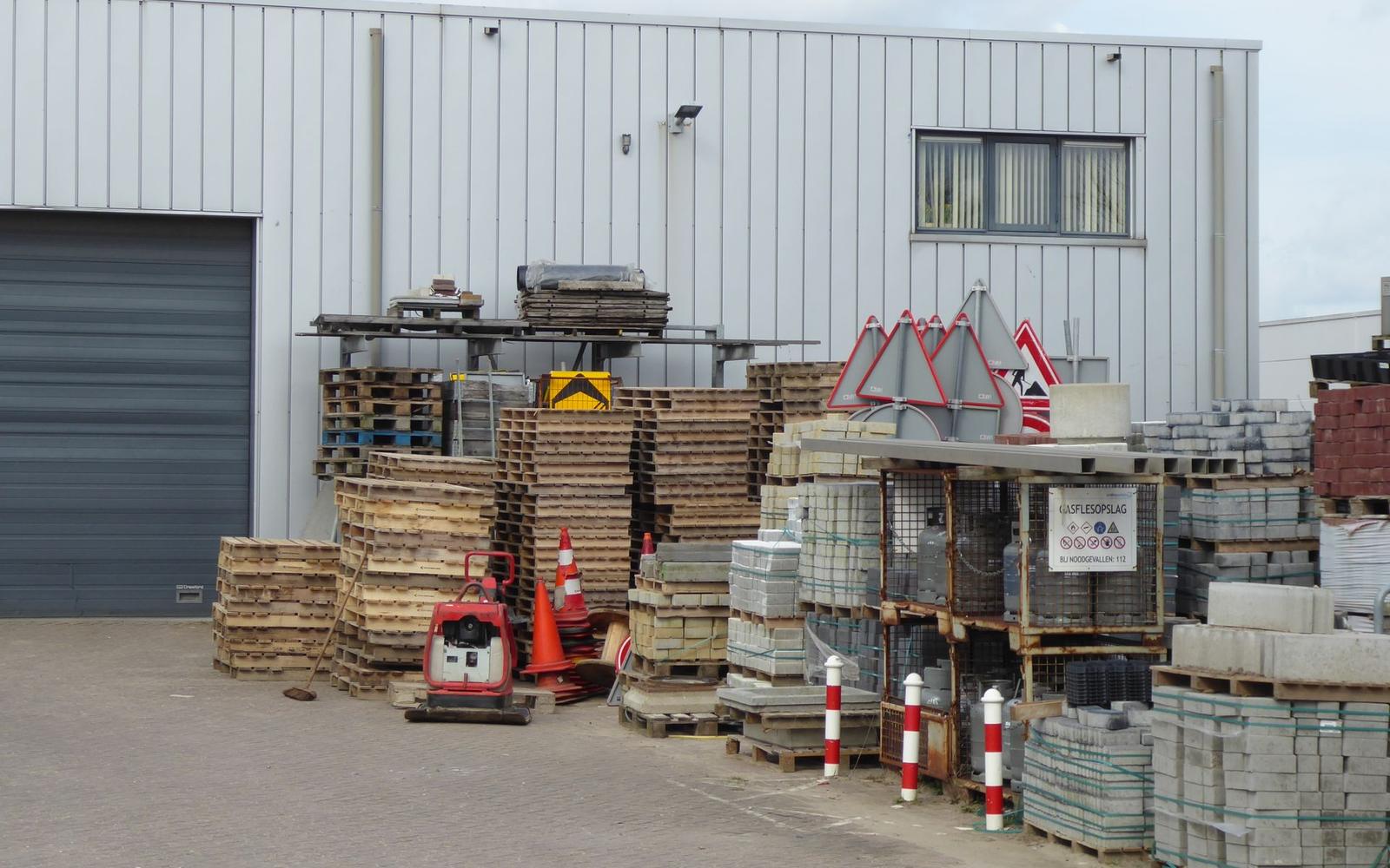 An industrial yard with stacked pallets, steel drums, and traffic cones staged for commercial haul-off.