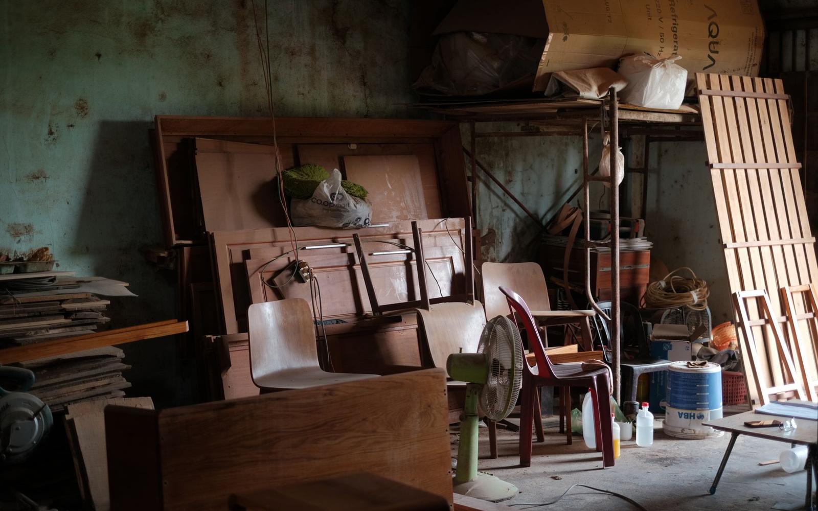 A storage room packed with old wooden furniture and household items during a property cleanout.